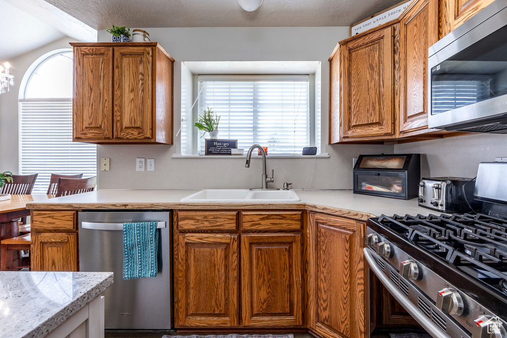 Kitchen featuring vaulted ceiling, stainless steel appliances, sink, and a notable chandelier