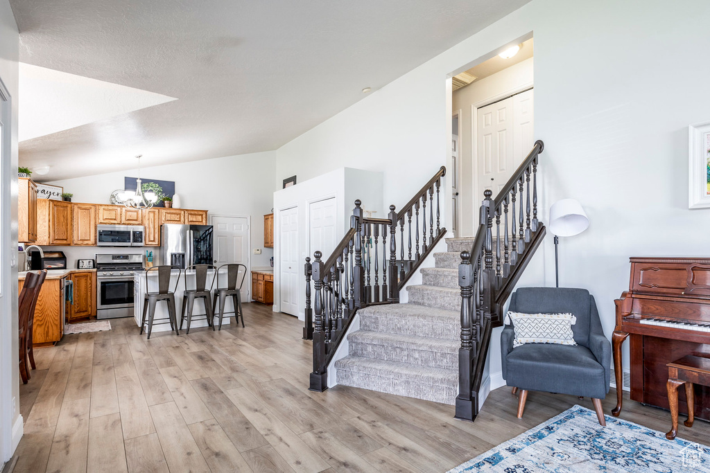 Stairway with high vaulted ceiling, hardwood / wood-style flooring, and a chandelier