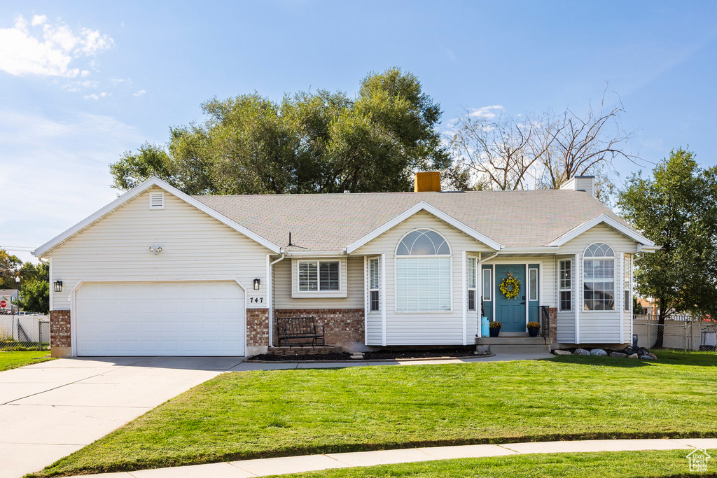 Ranch-style home featuring a front lawn and a garage