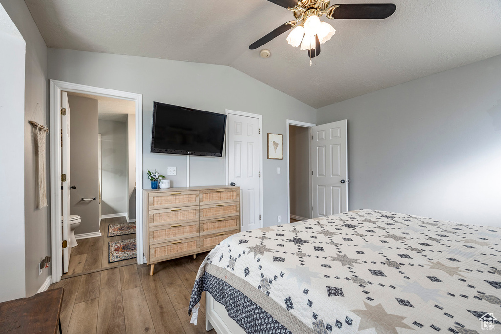 Bedroom featuring lofted ceiling, hardwood / wood-style floors, ensuite bathroom, and ceiling fan