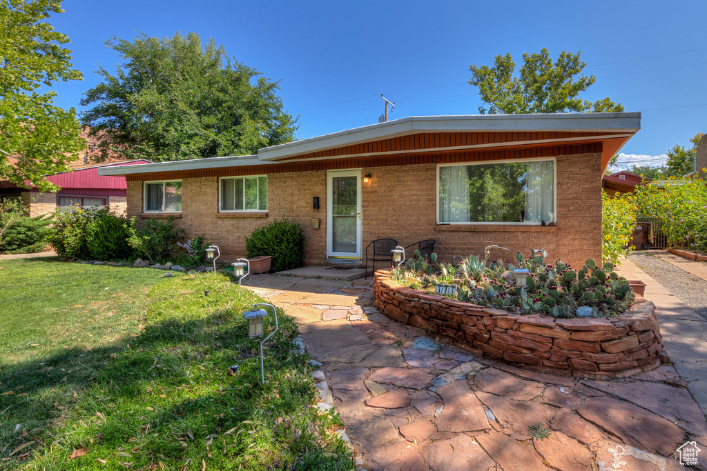 View of front of home featuring a patio area, a front yard, and brick siding