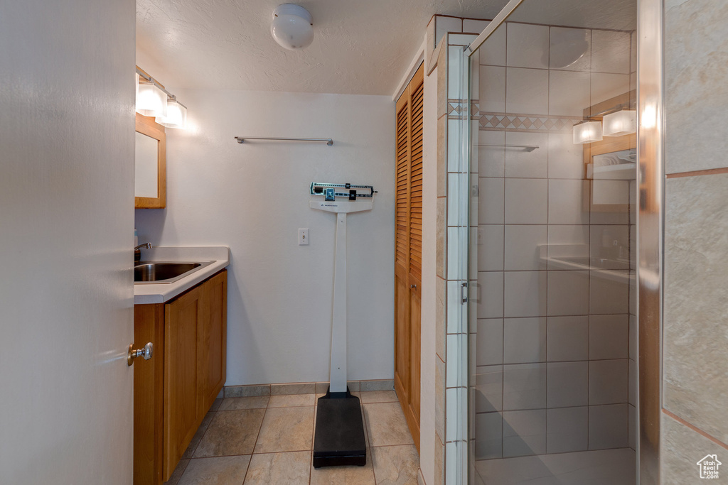 Full bathroom featuring tile patterned flooring, baseboards, a shower stall, and vanity