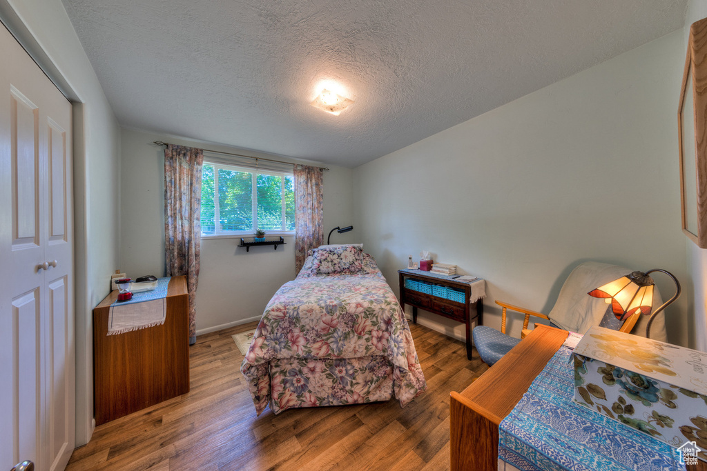 Bedroom with baseboards, wood finished floors, and a textured ceiling