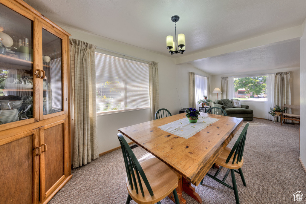 Dining area featuring baseboards, vaulted ceiling, a notable chandelier, and light carpet
