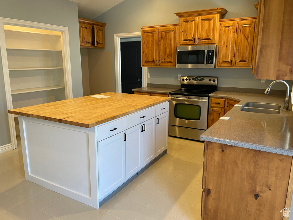 Kitchen with a kitchen island, vaulted ceiling, stainless steel appliances, sink, and white cabinets