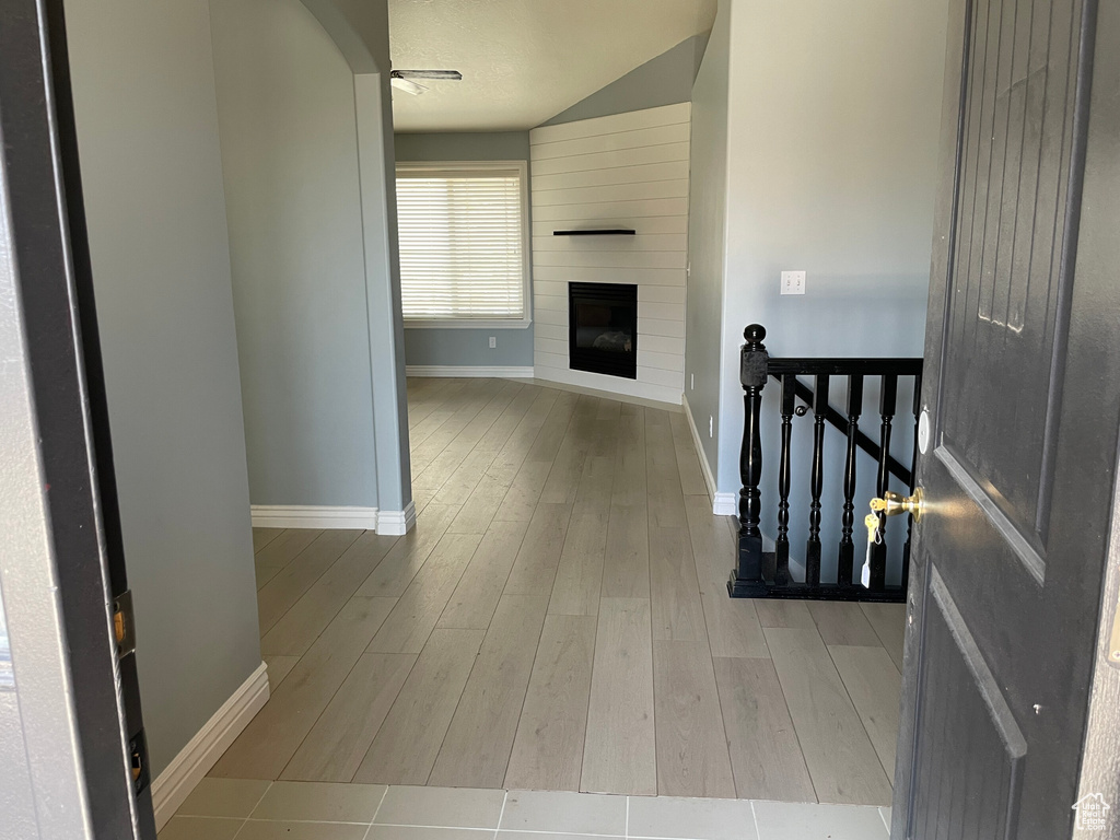 Hall featuring a textured ceiling, light hardwood / wood-style flooring, and lofted ceiling