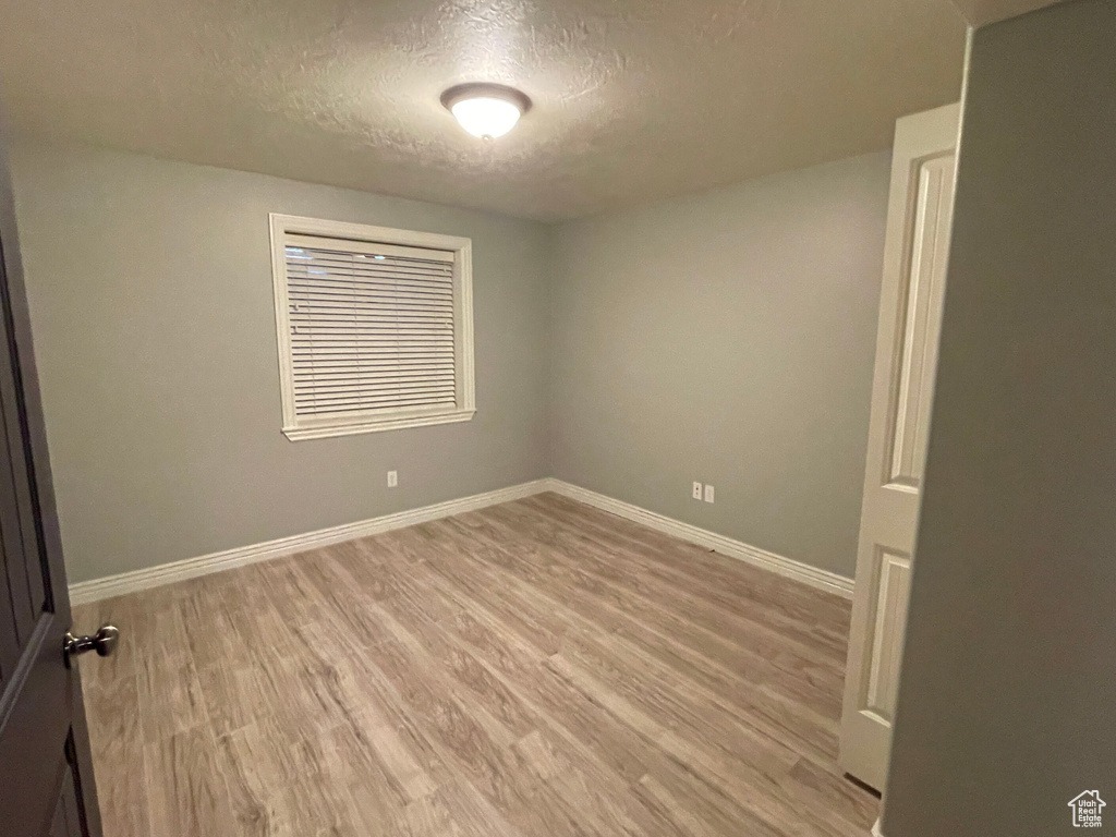 Spare room featuring light wood-type flooring and a textured ceiling