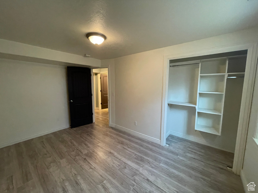 Unfurnished bedroom with a textured ceiling, a closet, and wood-type flooring