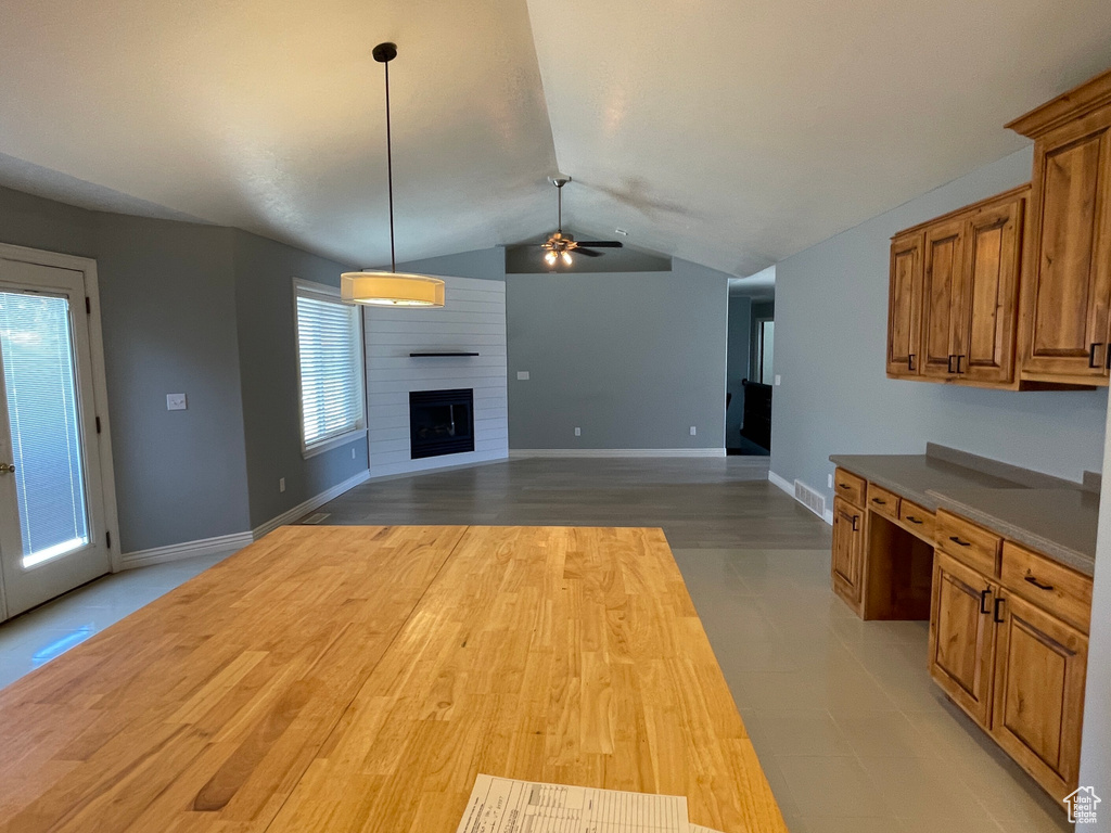 Kitchen featuring lofted ceiling, a large fireplace, ceiling fan, and light hardwood / wood-style floors