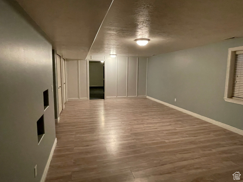 Basement with a textured ceiling and wood-type flooring