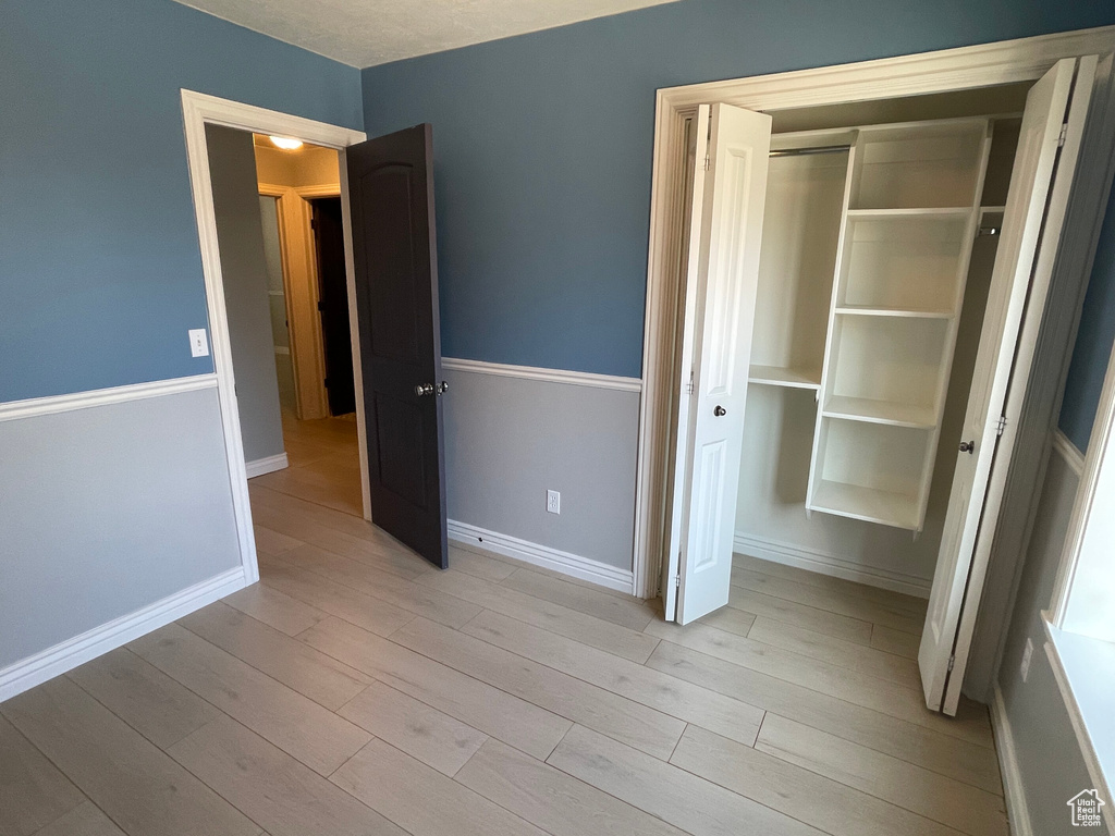 Unfurnished bedroom featuring light wood-type flooring, a closet, and a textured ceiling