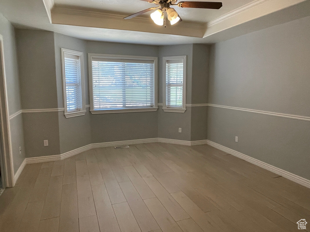 Spare room featuring hardwood / wood-style floors, ceiling fan, a tray ceiling, and crown molding