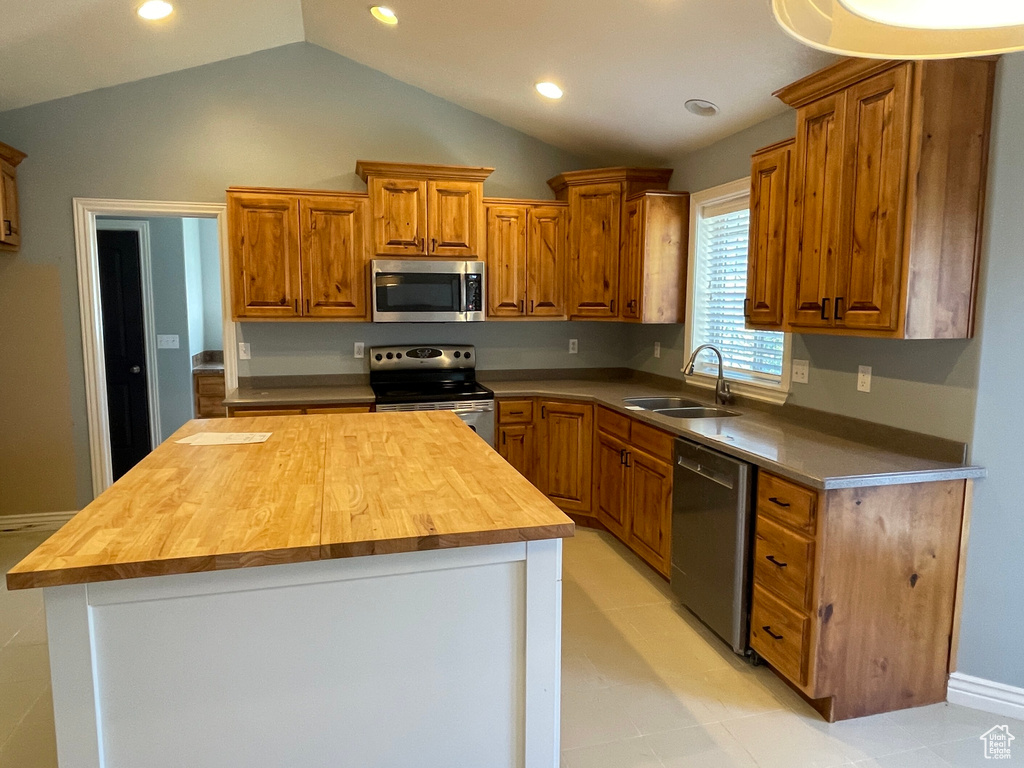 Kitchen with lofted ceiling, wood counters, stainless steel appliances, and sink