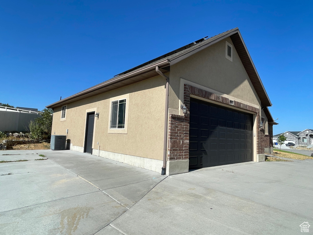 View of side of property with central air condition unit and a garage