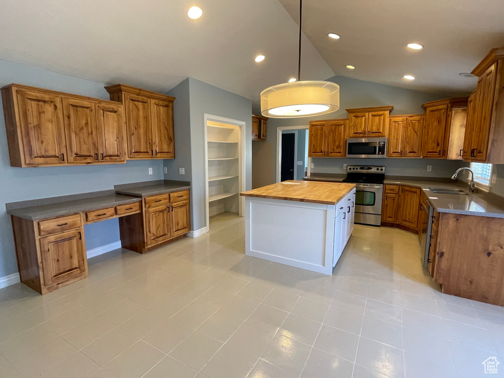 Kitchen with stainless steel appliances, wood counters, a center island, sink, and lofted ceiling