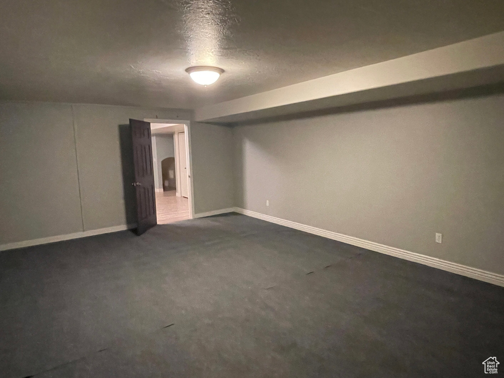 Basement featuring a textured ceiling and dark carpet