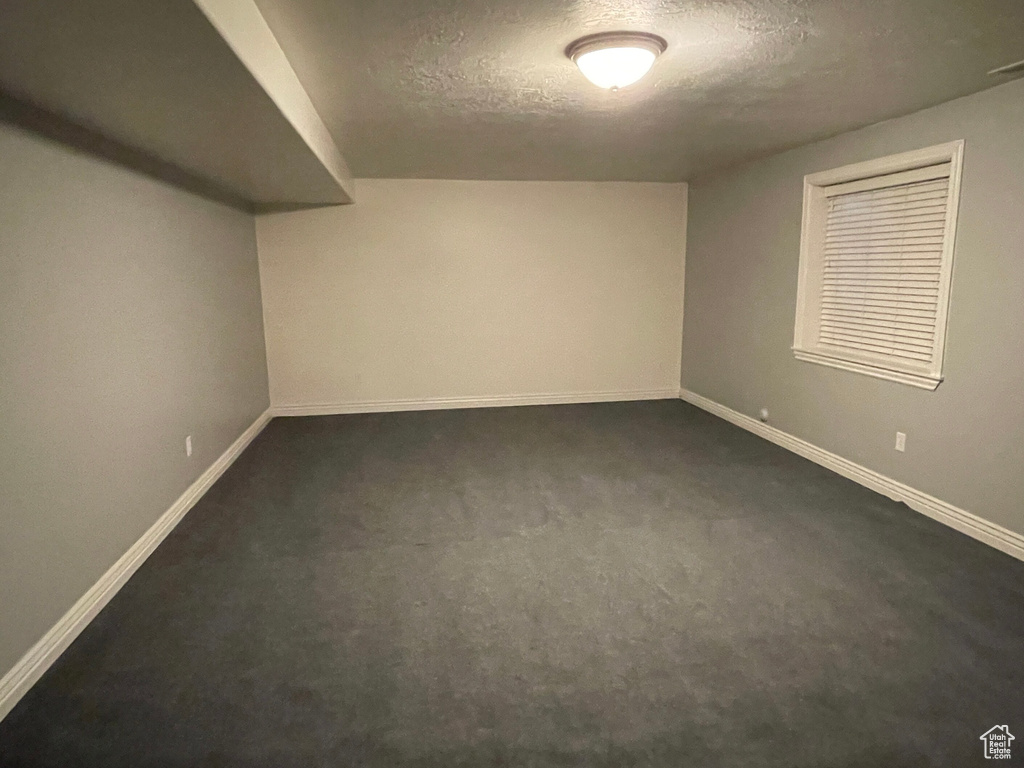 Bonus room featuring a textured ceiling and dark carpet