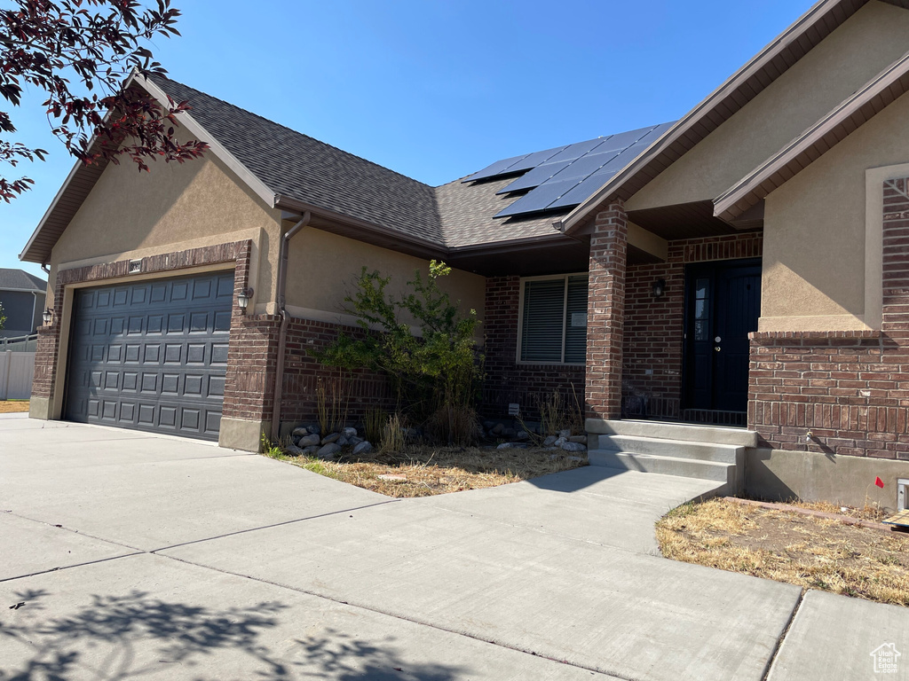 View of front of home featuring a garage and solar panels