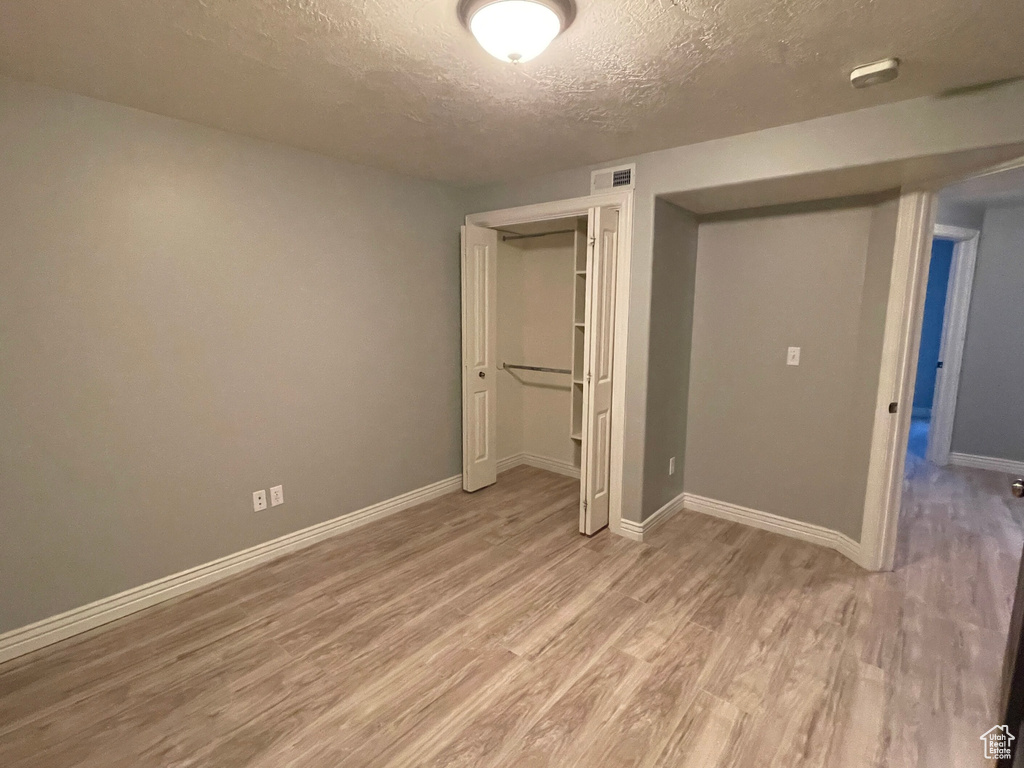 Unfurnished bedroom with a closet, light hardwood / wood-style floors, and a textured ceiling