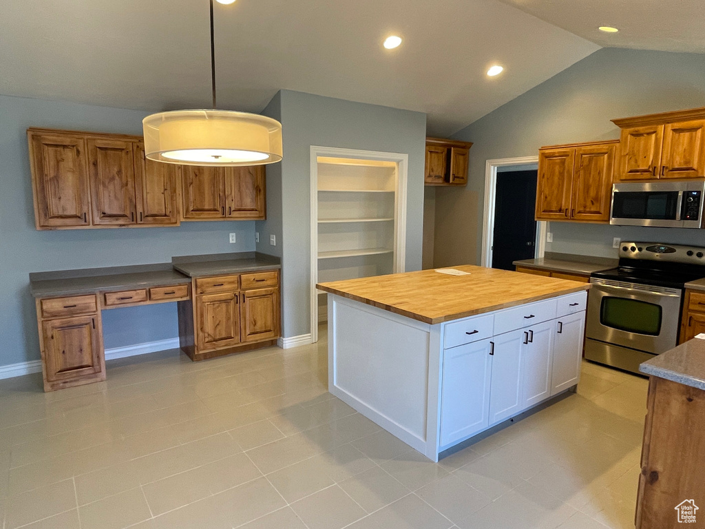 Kitchen with white cabinetry, stainless steel appliances, wooden counters, vaulted ceiling, and light tile patterned flooring