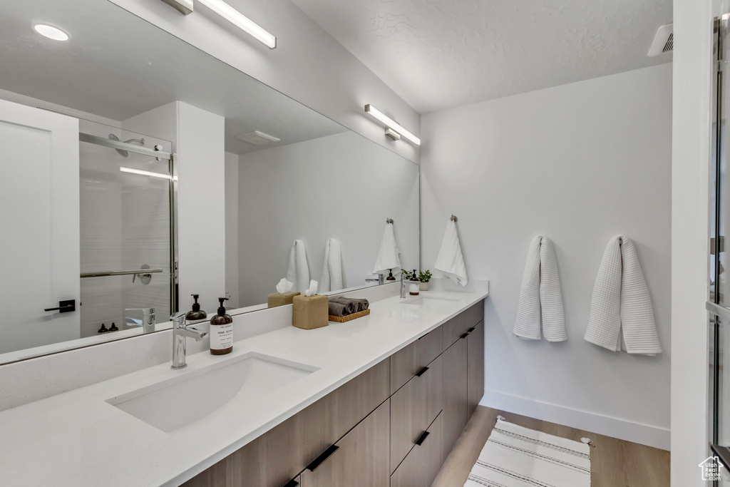 Bathroom with hardwood / wood-style floors, walk in shower, and vanity