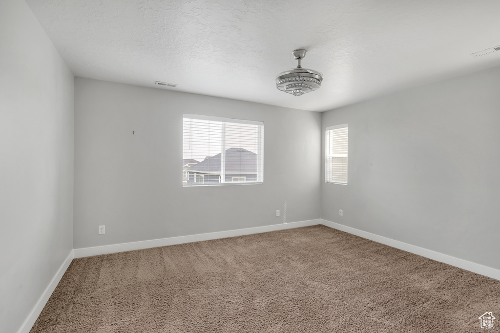 Empty room featuring carpet flooring and a textured ceiling