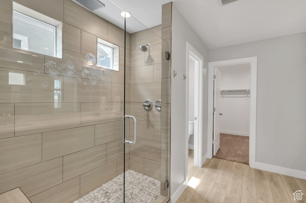 Bathroom with toilet, wood-type flooring, and an enclosed shower