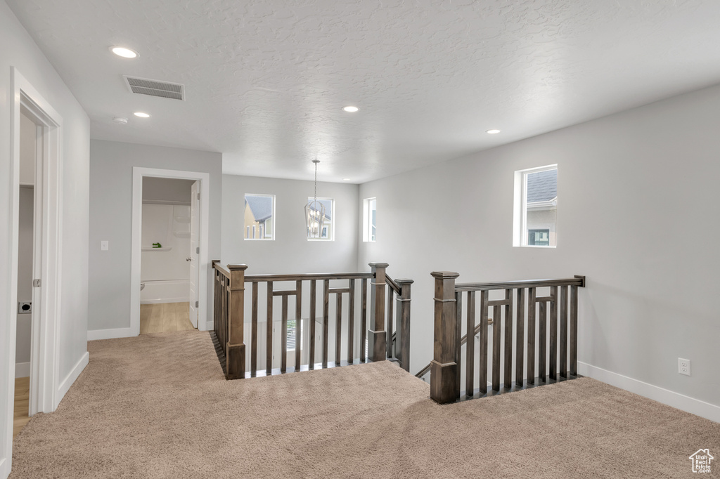 Corridor featuring light carpet and a textured ceiling