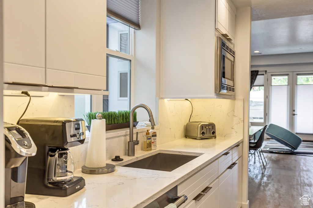 Kitchen with light stone countertops, sink, and white cabinets