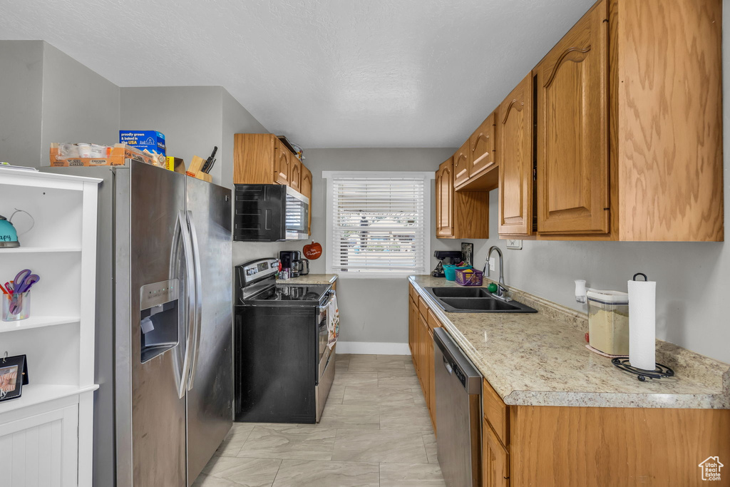 Kitchen featuring a textured ceiling, stainless steel appliances, and sink