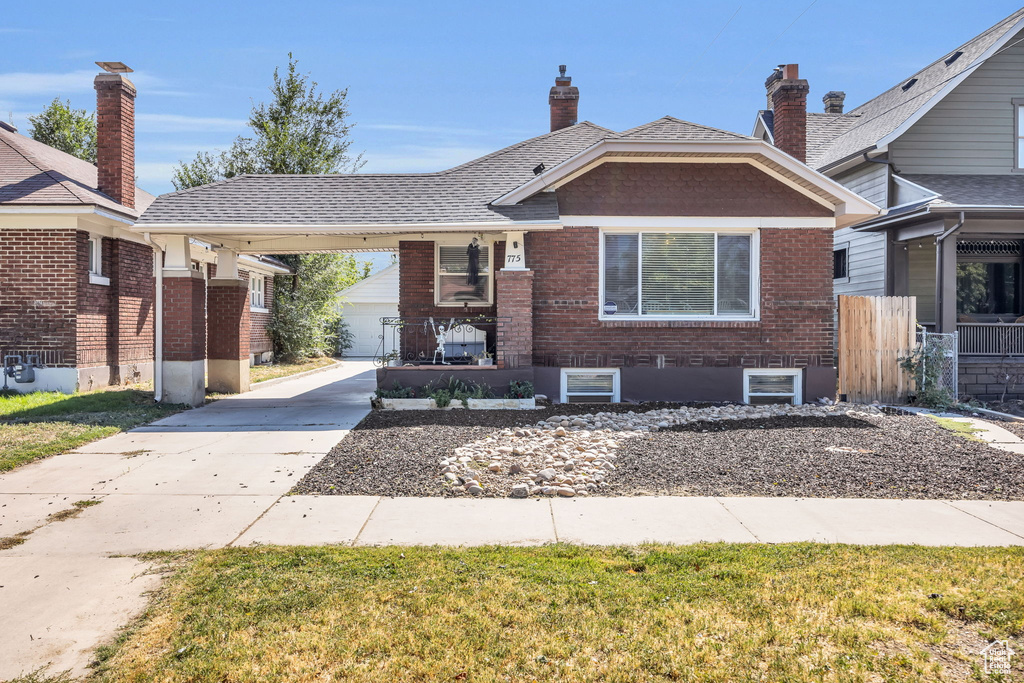 View of front of house featuring covered porch, a carport, and a front lawn