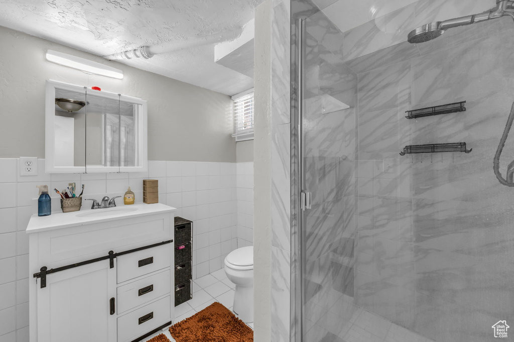 Bathroom featuring vanity, toilet, walk in shower, and tile walls