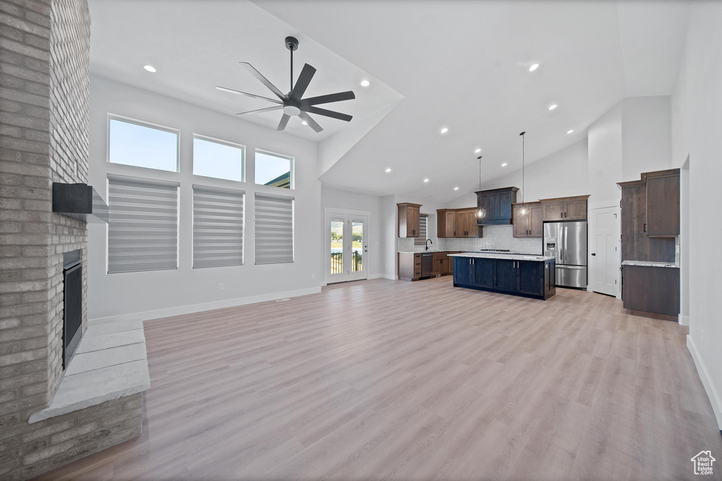 Living room featuring a fireplace, high vaulted ceiling, sink, ceiling fan, and light hardwood / wood-style floors