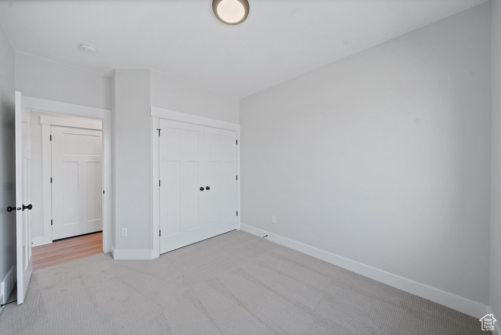 Unfurnished bedroom featuring light colored carpet and a closet