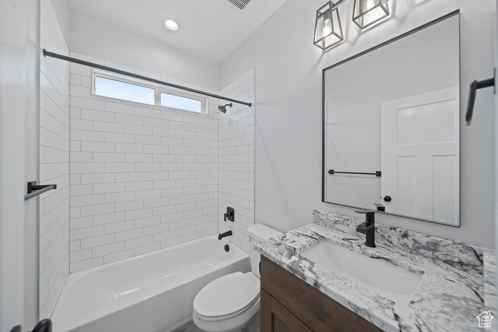 Full bathroom featuring vanity, toilet, and tiled shower / bath combo