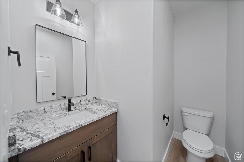 Bathroom featuring wood-type flooring, toilet, and vanity