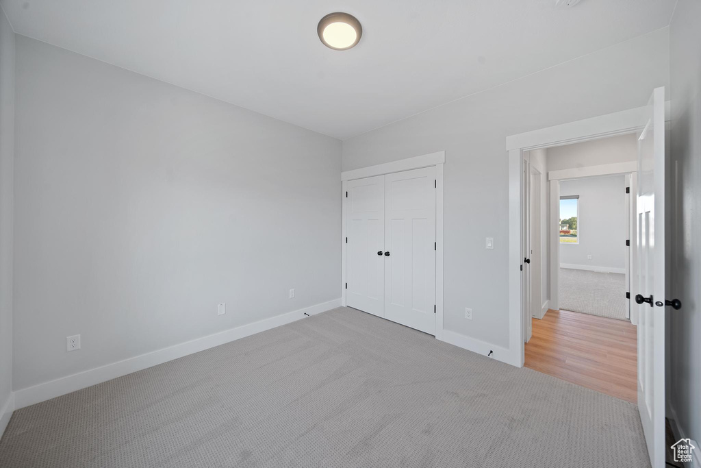 Unfurnished bedroom featuring light carpet and a closet