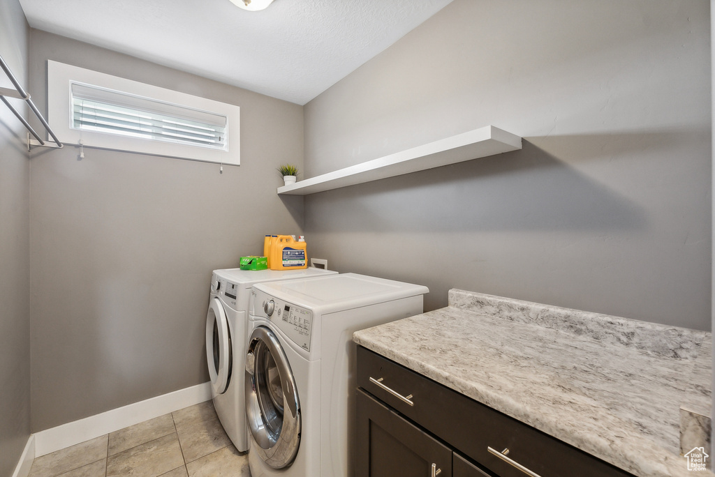 Washroom with washing machine and clothes dryer and light tile patterned floors