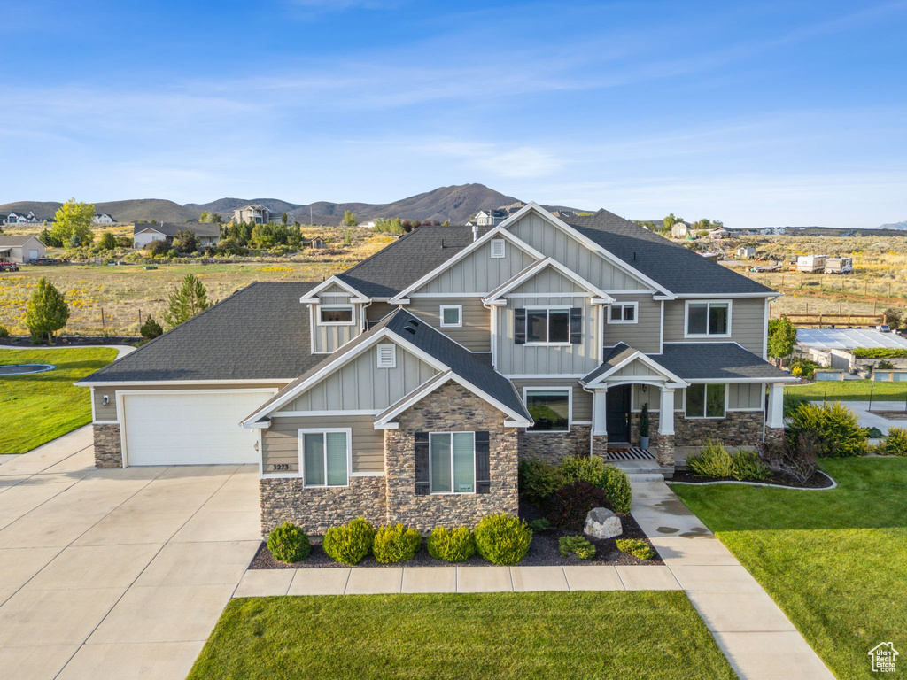 Craftsman-style home with a front lawn, a garage, and a mountain view