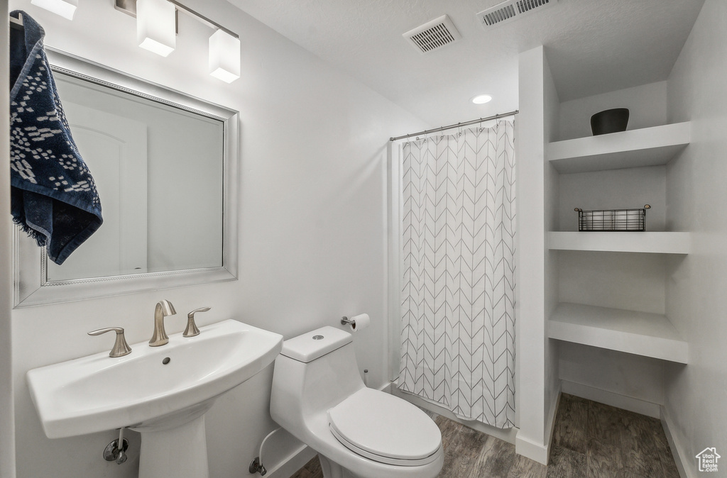 Bathroom with toilet, a shower with curtain, hardwood / wood-style floors, and sink