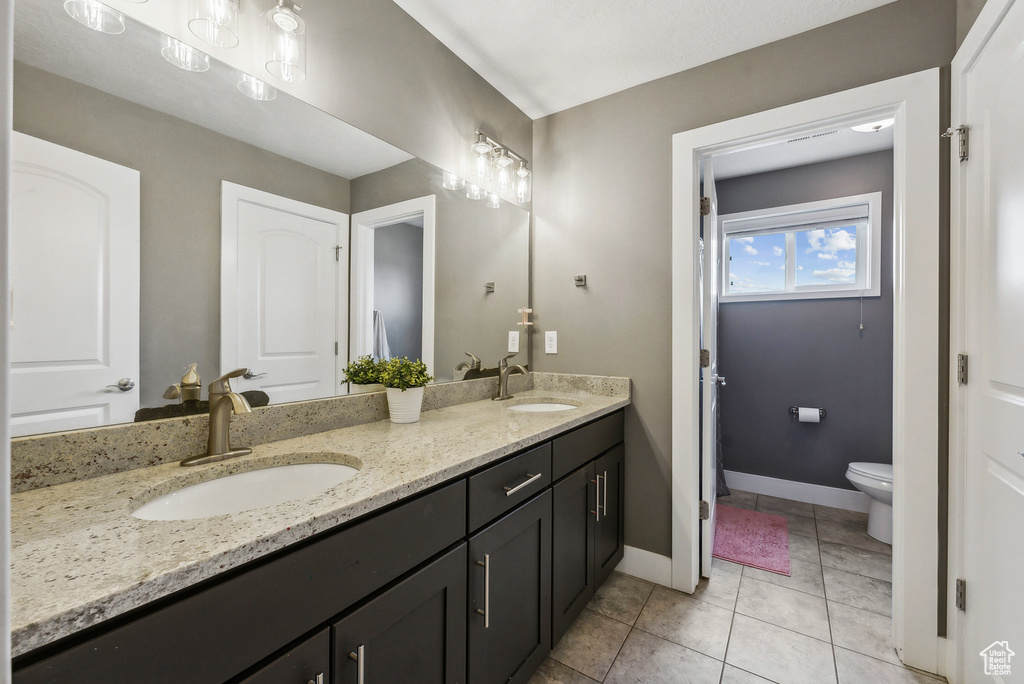 Bathroom featuring vanity, toilet, and tile patterned flooring