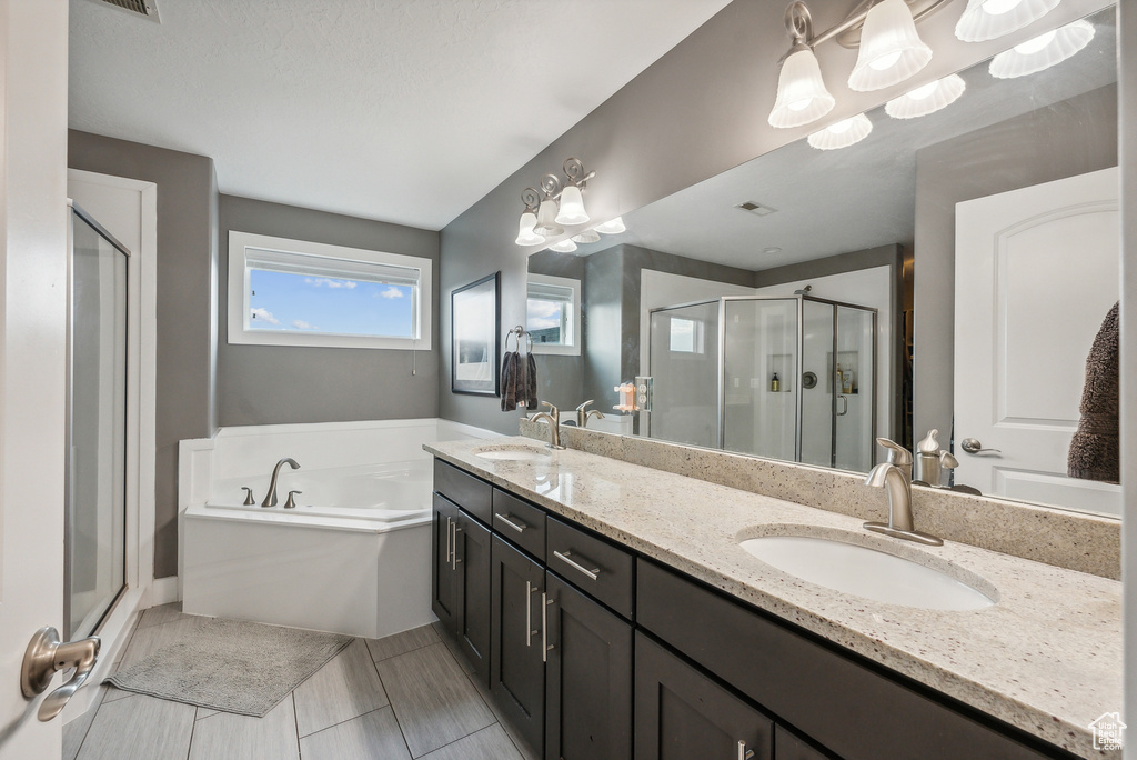 Bathroom with tile patterned flooring, shower with separate bathtub, a notable chandelier, and vanity