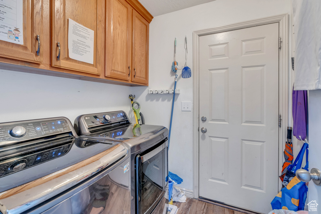 Laundry area with hardwood / wood-style flooring, cabinets, and separate washer and dryer