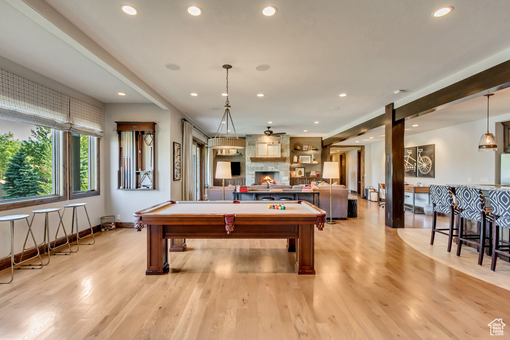 Rec room featuring bar, pool table, light hardwood / wood-style floors, and a stone fireplace