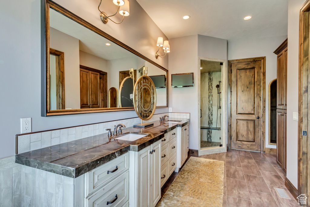 Bathroom with tile patterned floors, a shower with door, tasteful backsplash, and vanity