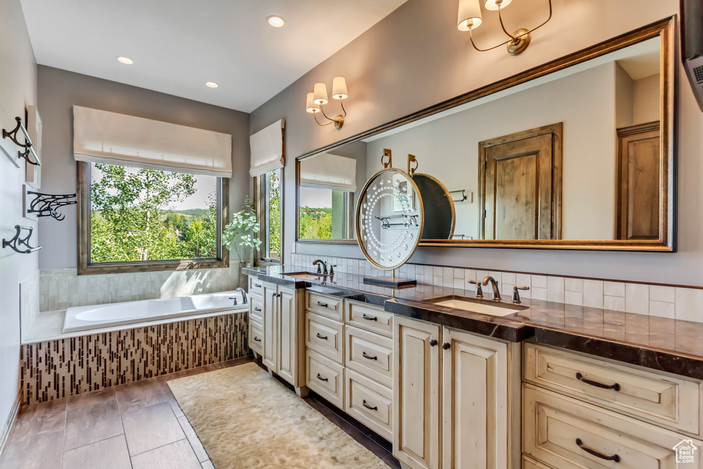 Bathroom with vanity, backsplash, tile patterned floors, and tiled bath