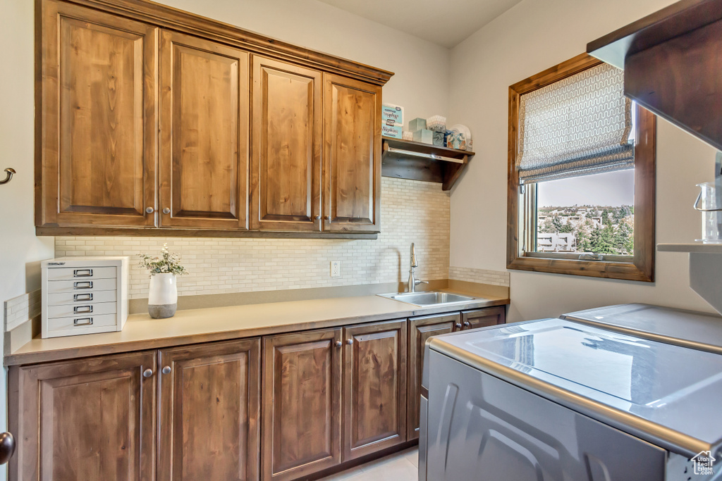 Kitchen with range hood, backsplash, washing machine and clothes dryer, and sink