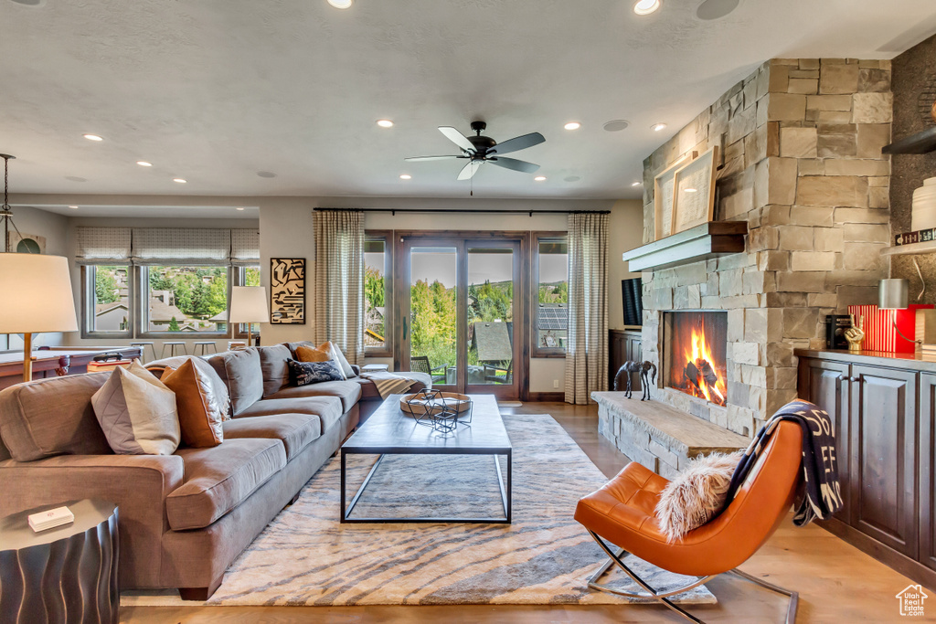 Living room with plenty of natural light, a stone fireplace, and light wood-type flooring