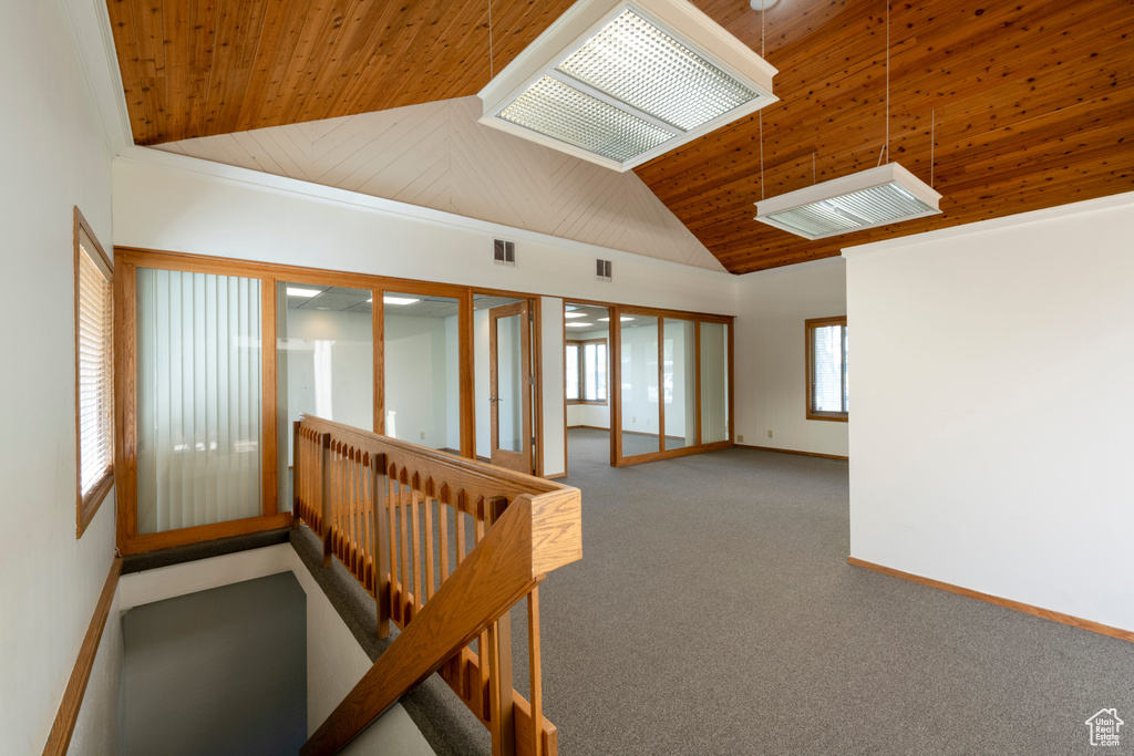Carpeted spare room featuring wood ceiling, ornamental molding, and high vaulted ceiling