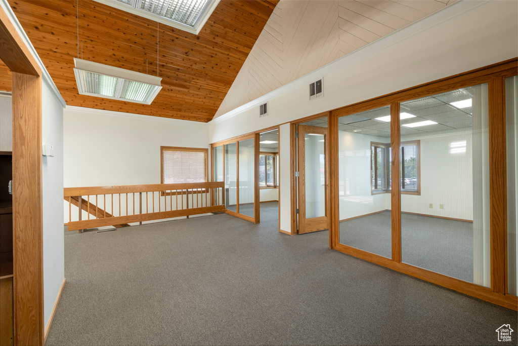 Carpeted empty room with wood ceiling and high vaulted ceiling